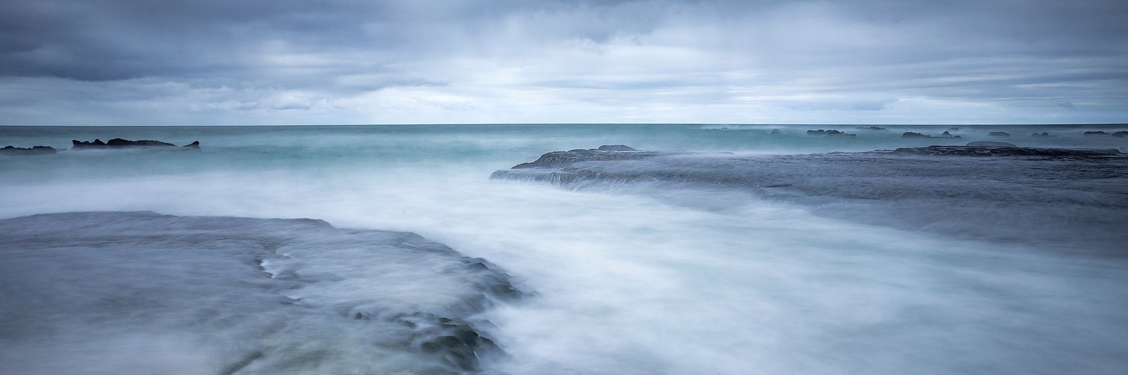 Long exposure of the sea washing over flat rocks at Stilbaai