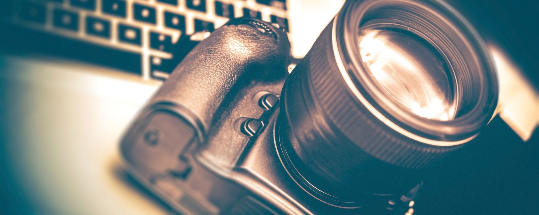 A modern DSLR camera paired with an interchangeable lens, arranged on a sleek surface to highlight learning photography