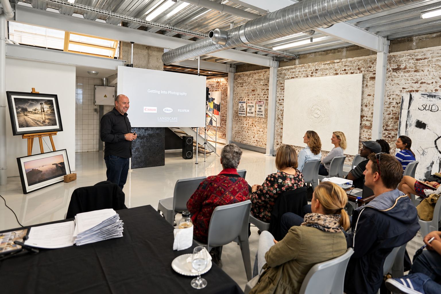 Martin Osner teaching a full room of students in the studio, beside framed prints